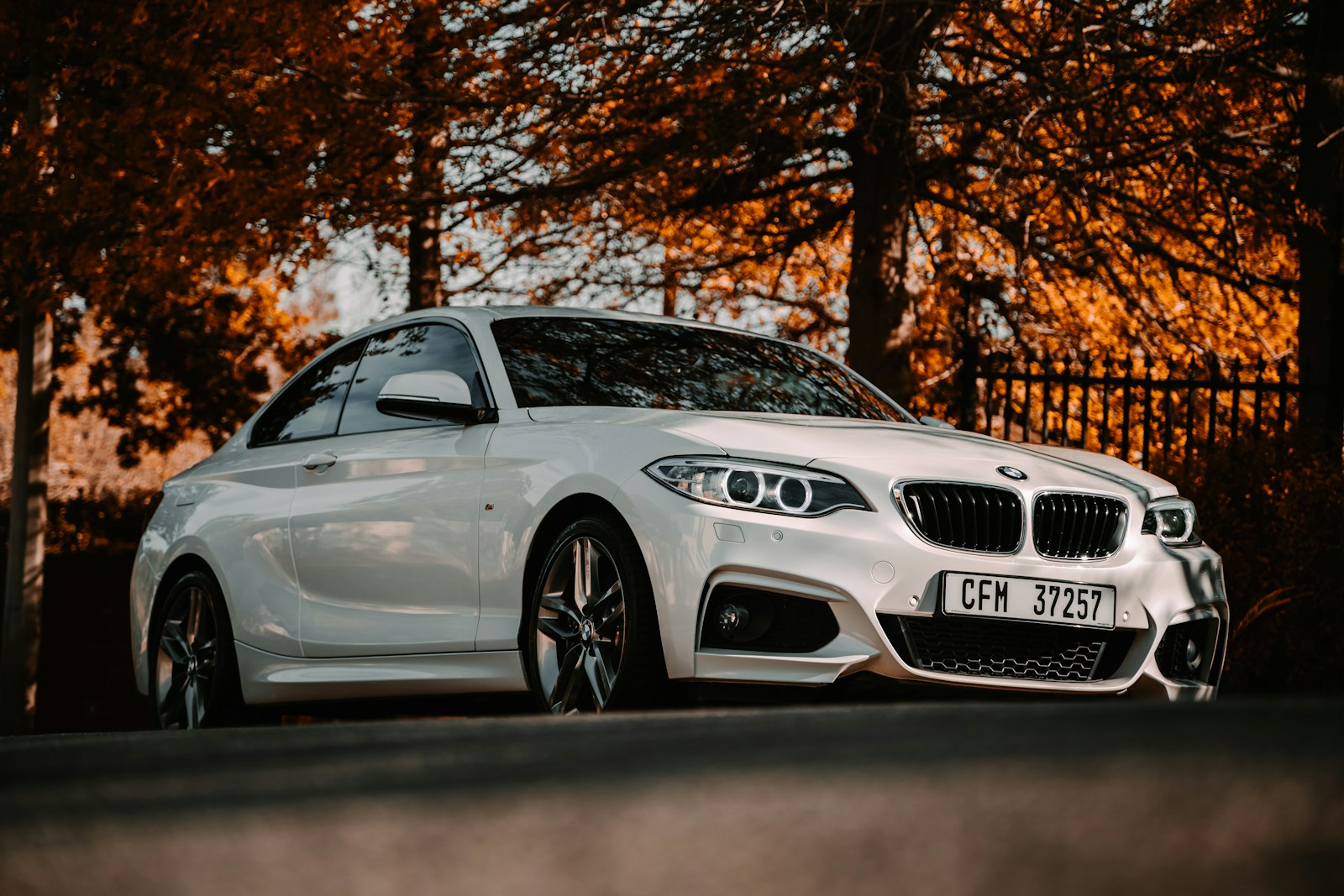 Photo by Stephan Louis white bmw m 3 coupe parked near brown trees during daytime