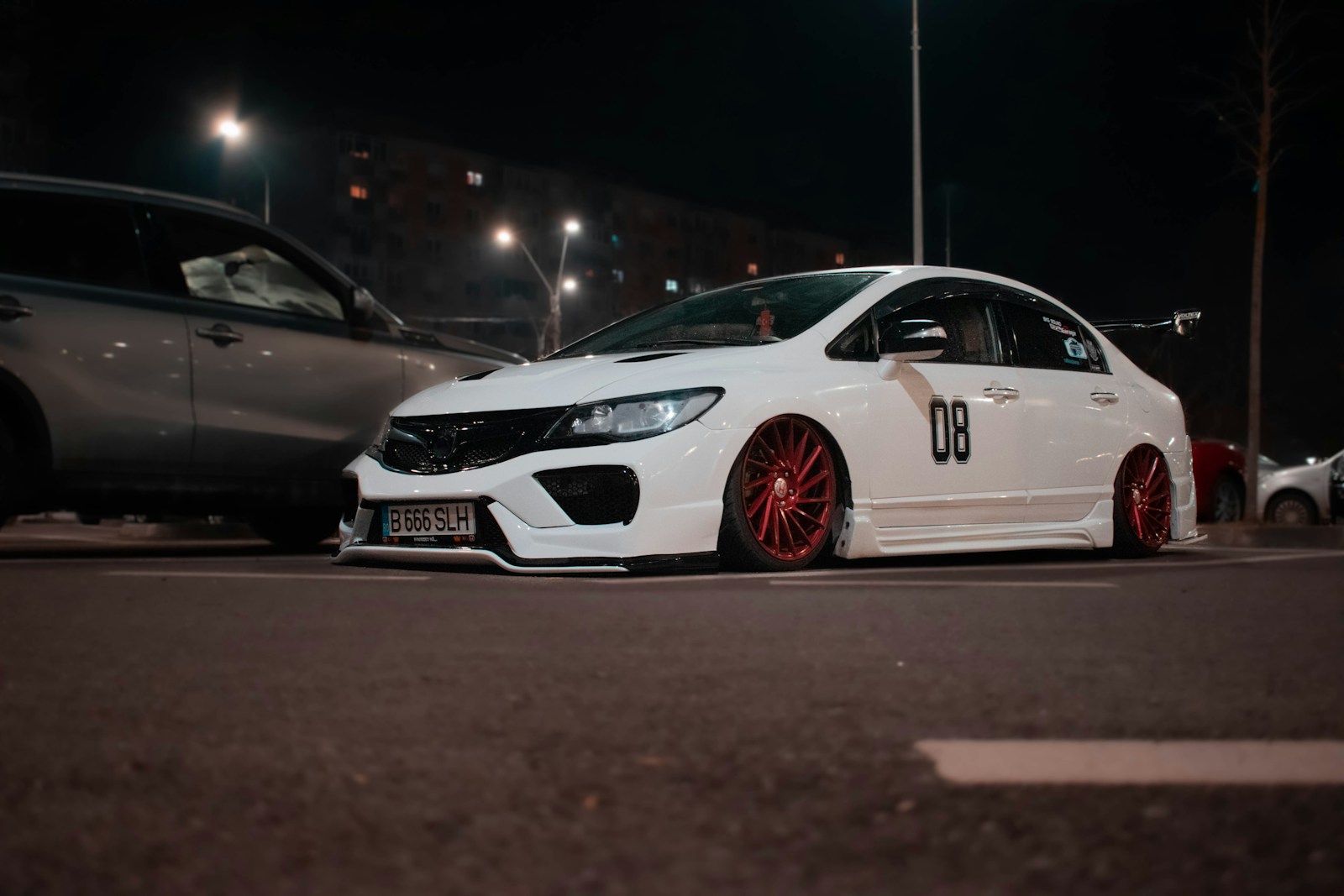 a white car with red rims parked in a parking lot